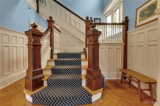 stairs featuring wainscoting and a decorative wall
