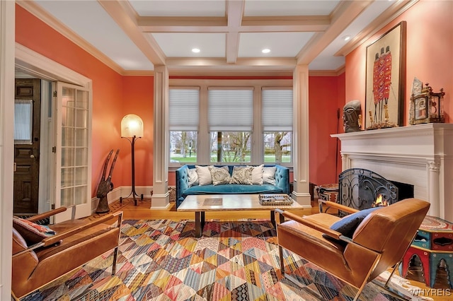 living area with beamed ceiling, coffered ceiling, a warm lit fireplace, baseboards, and ornamental molding