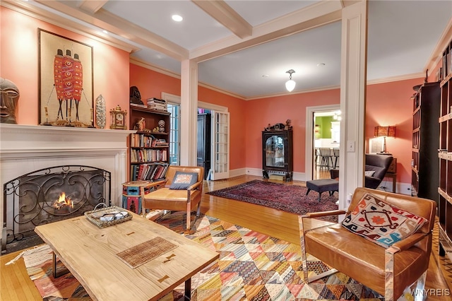 living room with a lit fireplace, beam ceiling, recessed lighting, ornamental molding, and wood finished floors