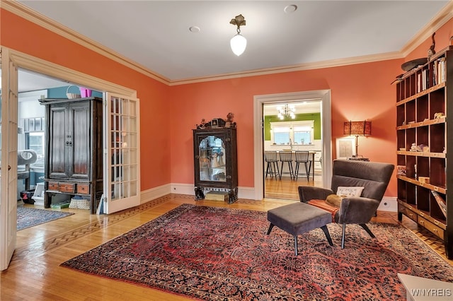 sitting room with an inviting chandelier, wood finished floors, ornamental molding, and baseboards