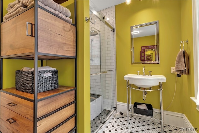 full bath with a sink, a shower stall, and baseboards