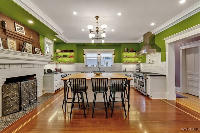kitchen with double oven range, wood counters, open shelves, and wall chimney range hood
