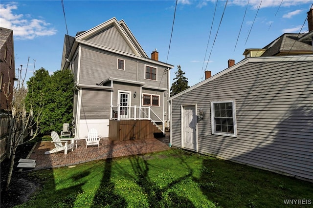 rear view of house featuring a chimney, fence, a yard, and a patio area