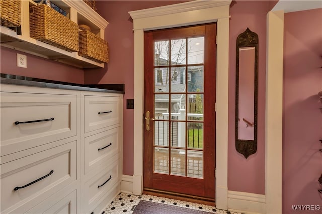 doorway to outside with baseboards and tile patterned flooring