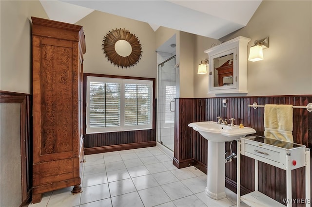 bathroom with tile patterned floors, a wainscoted wall, a shower stall, and lofted ceiling