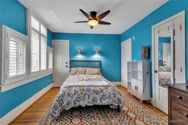 bedroom with wood finished floors, a ceiling fan, and baseboards
