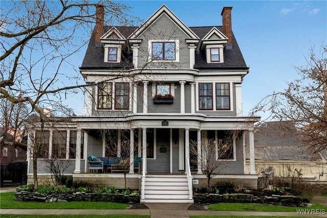 view of front facade featuring a chimney and a porch