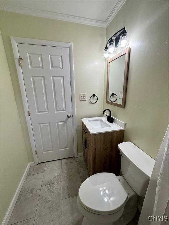 bathroom featuring marble finish floor, toilet, vanity, baseboards, and crown molding