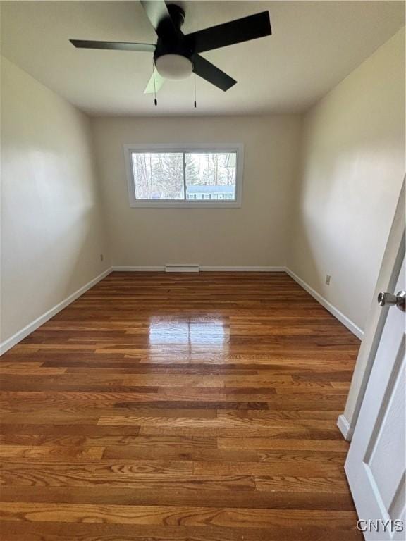 unfurnished room featuring ceiling fan, wood finished floors, and baseboards