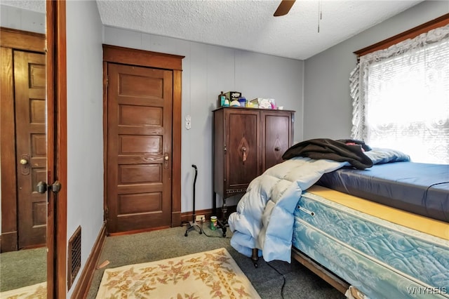 carpeted bedroom featuring a textured ceiling, visible vents, and ceiling fan