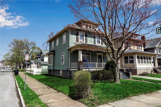 traditional style home with a porch, a residential view, and a front yard