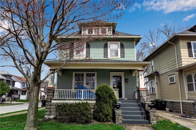 traditional style home with a porch and roof with shingles