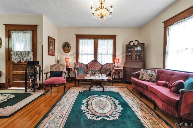 living area with a notable chandelier, wood finished floors, and plenty of natural light