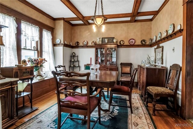 dining room featuring beamed ceiling, coffered ceiling, and wood finished floors