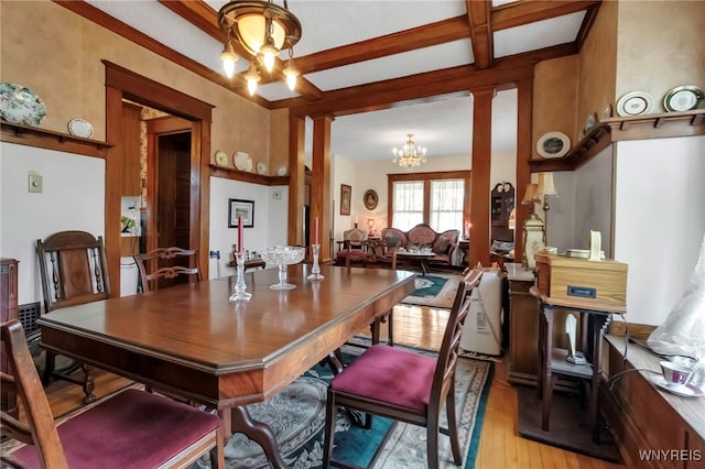dining area featuring light wood-style floors, a notable chandelier, beamed ceiling, and decorative columns