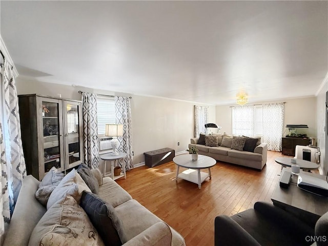 living room with ornamental molding, cooling unit, baseboards, and light wood-style floors