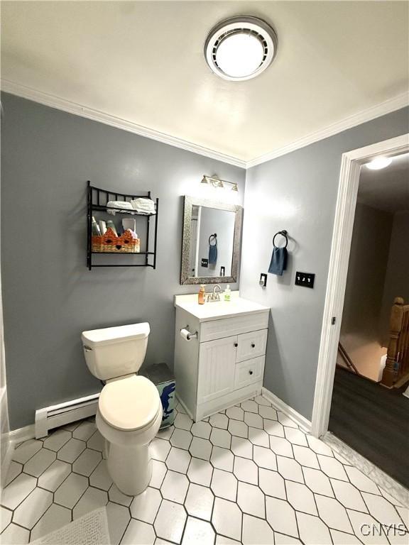 bathroom with a baseboard heating unit, ornamental molding, toilet, vanity, and baseboards