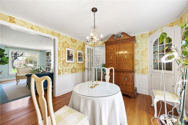 422 Salt Springs Rd, Manlius, NY 13066 - dining area featuring wood finished floors, a notable chandelier, wallpapered walls, and wainscoting