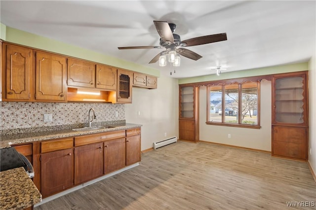 1631 Tuscarora Rd, Niagara, NY 14304 - kitchen featuring tasteful backsplash, a sink, baseboard heating, light wood-type flooring, and brown cabinetry