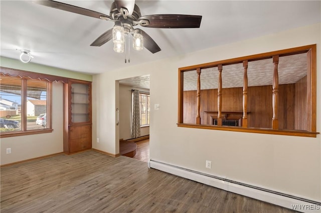 1631 Tuscarora Rd, Niagara, NY 14304 - unfurnished room featuring a ceiling fan, wood finished floors, a baseboard heating unit, and plenty of natural light