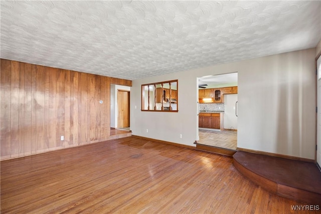1631 Tuscarora Rd, Niagara, NY 14304 - unfurnished living room with a textured ceiling, wood walls, wood finished floors, and baseboards