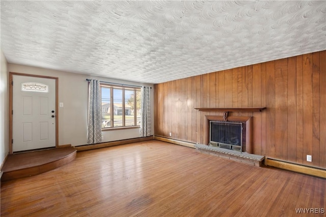 1631 Tuscarora Rd, Niagara, NY 14304 - unfurnished living room featuring a textured ceiling, wood walls, a baseboard radiator, a fireplace, and wood finished floors