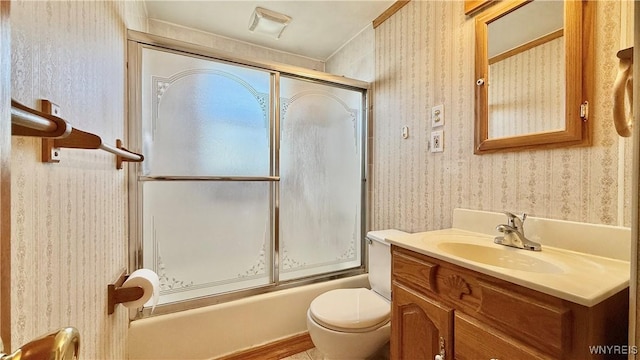 bathroom featuring combined bath / shower with glass door, wallpapered walls, toilet, and vanity