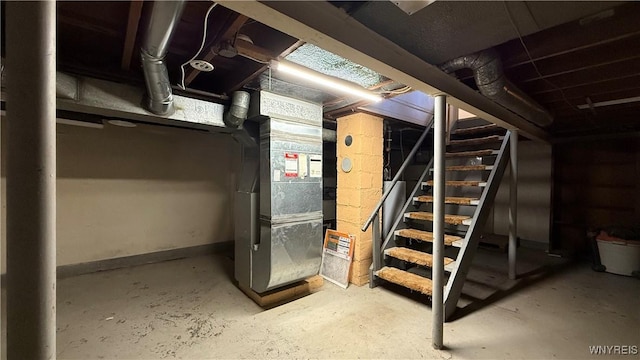 unfinished basement featuring stairway, heating unit, and baseboards
