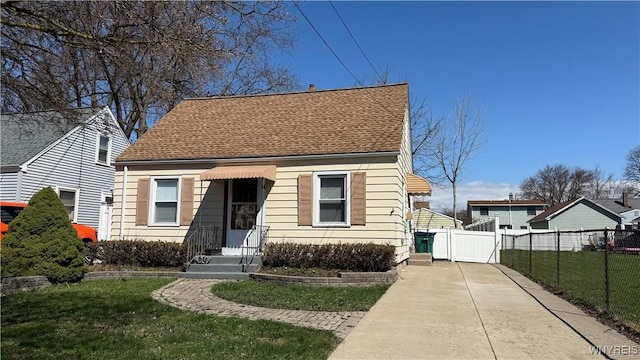 view of front of home with fence, a front lawn, concrete driveway, and roof with shingles