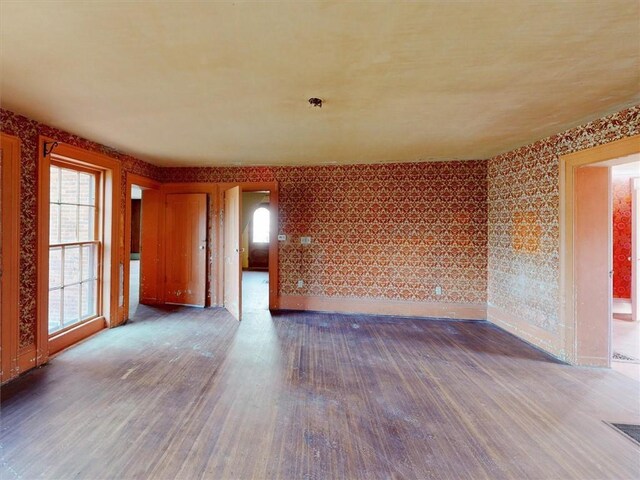 spare room with visible vents, wallpapered walls, and wood finished floors