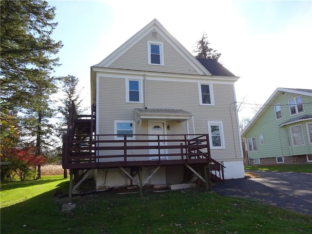 rear view of house featuring a yard, a wooden deck, and stairs