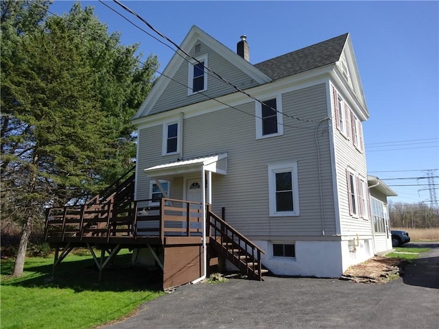 view of front of property featuring a shingled roof, a chimney, and a deck