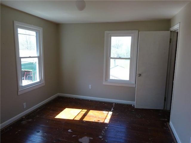 empty room with baseboards, plenty of natural light, and hardwood / wood-style floors