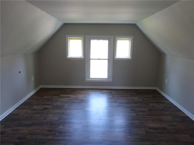 additional living space with baseboards, dark wood-style floors, and lofted ceiling