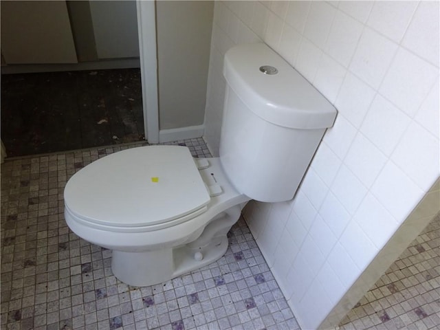 bathroom featuring tile patterned flooring, toilet, and tile walls