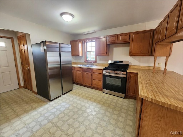 kitchen featuring stainless steel appliances, light floors, brown cabinets, and a sink