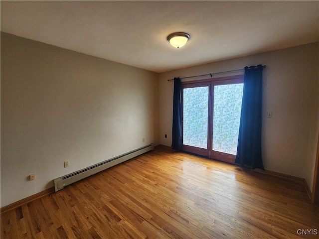 empty room featuring light wood-type flooring, a baseboard heating unit, and baseboards