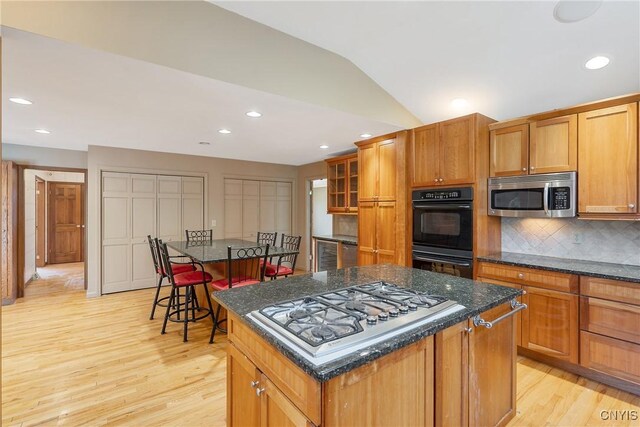 7266 Wakefield Dr, Manlius, NY 13066 - kitchen featuring a center island, light wood finished floors, stainless steel appliances, and decorative backsplash