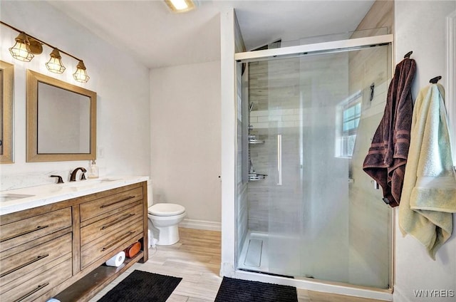 full bathroom featuring vanity, toilet, baseboards, a shower stall, and wood finished floors
