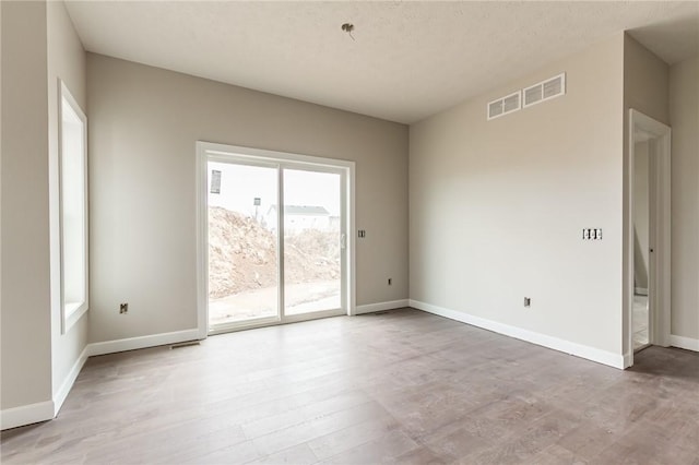 unfurnished room featuring visible vents, baseboards, and wood finished floors
