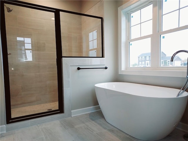 bathroom with baseboards, a freestanding tub, and a stall shower