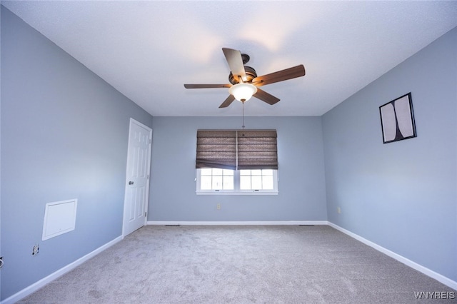 carpeted spare room with baseboards and a ceiling fan