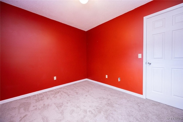 carpeted empty room featuring baseboards