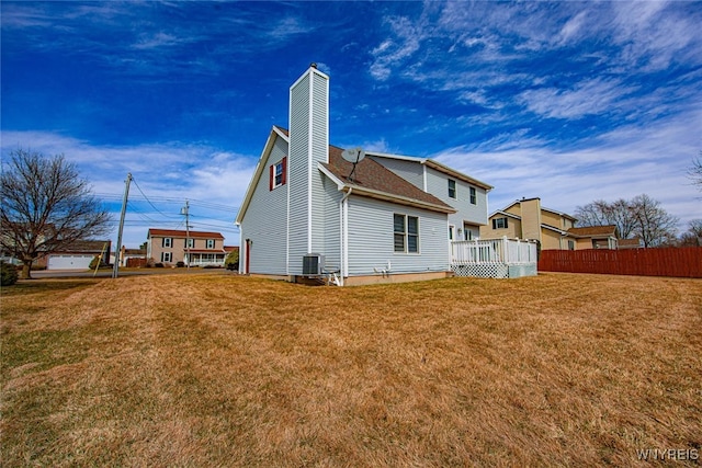rear view of property with a lawn, fence, roof with shingles, and a chimney