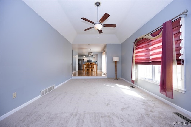 unfurnished living room with visible vents, ceiling fan, carpet floors, and vaulted ceiling