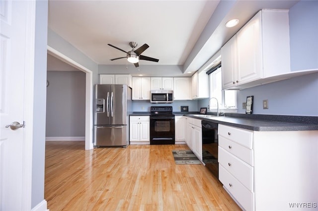 kitchen with white cabinetry, a sink, dark countertops, black appliances, and a ceiling fan