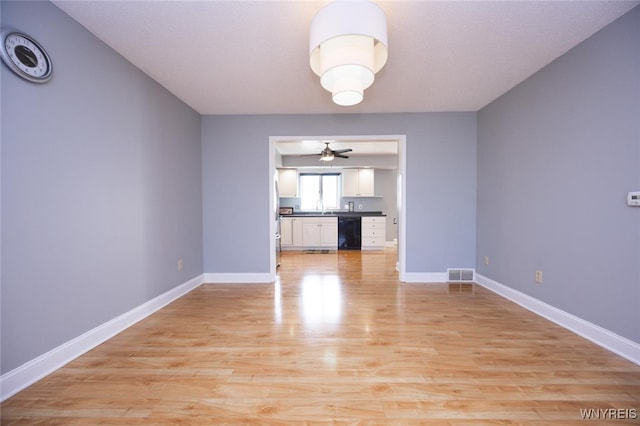 unfurnished dining area with visible vents, a ceiling fan, light wood-style flooring, and baseboards