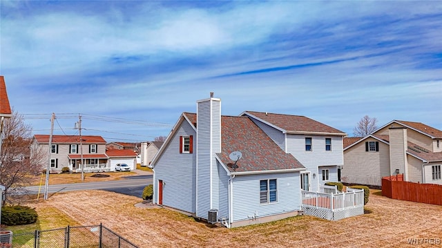 rear view of property featuring a residential view, fence, central air condition unit, and a chimney