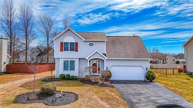 traditional-style home featuring driveway, fence, and a front lawn