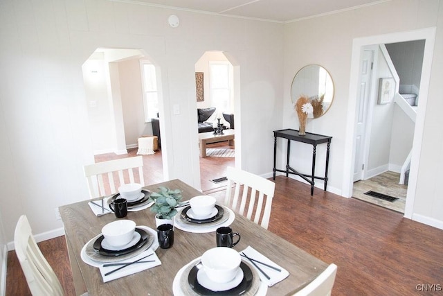 dining room featuring visible vents, arched walkways, ornamental molding, and wood finished floors